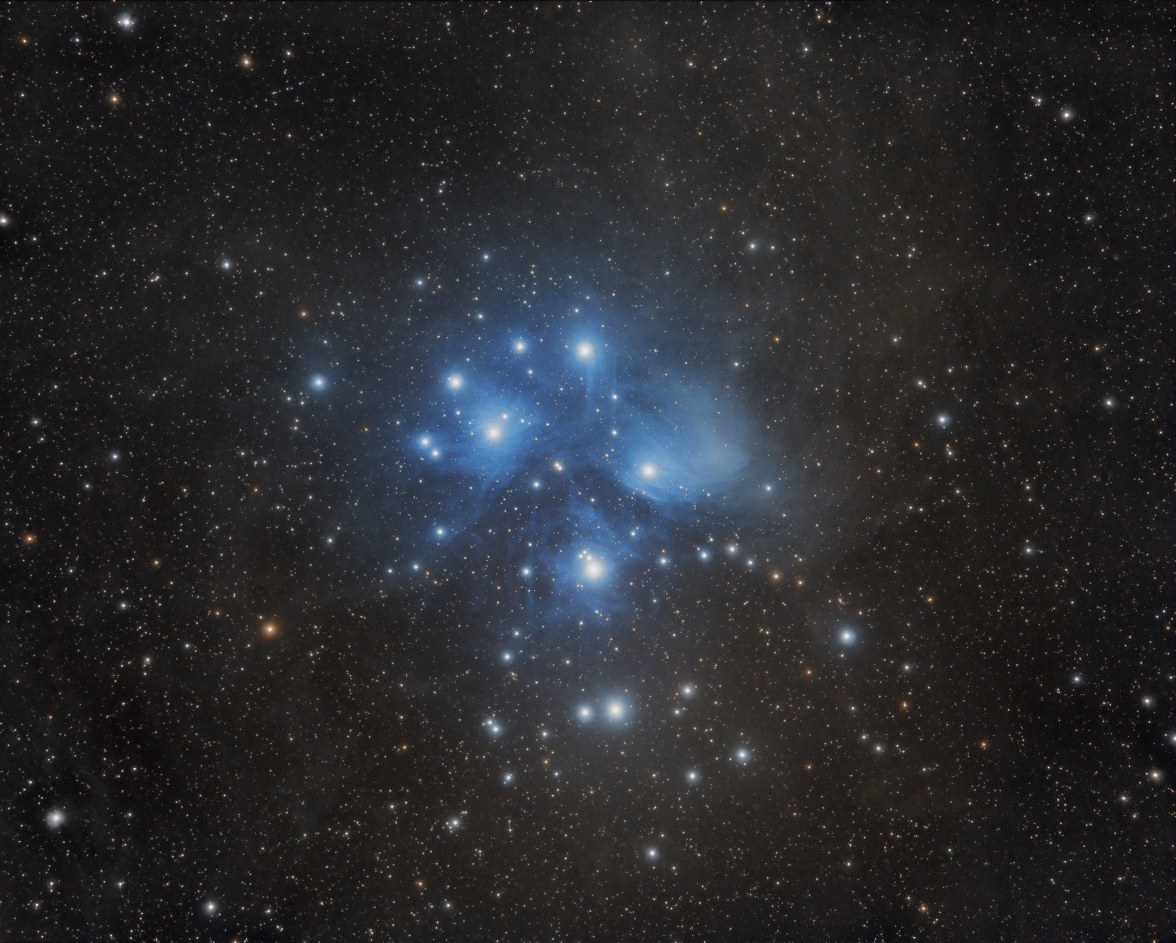 Astronomical image of a cluster of vivid blue stars against a black sky. There are about a dozen bright stars near the centre. The background contains innumerable faint stars of various colours.